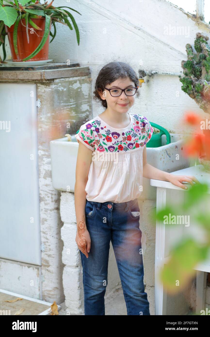 Petite fille debout autour des plantes en pot regardant dans l'appareil photo. Banque D'Images