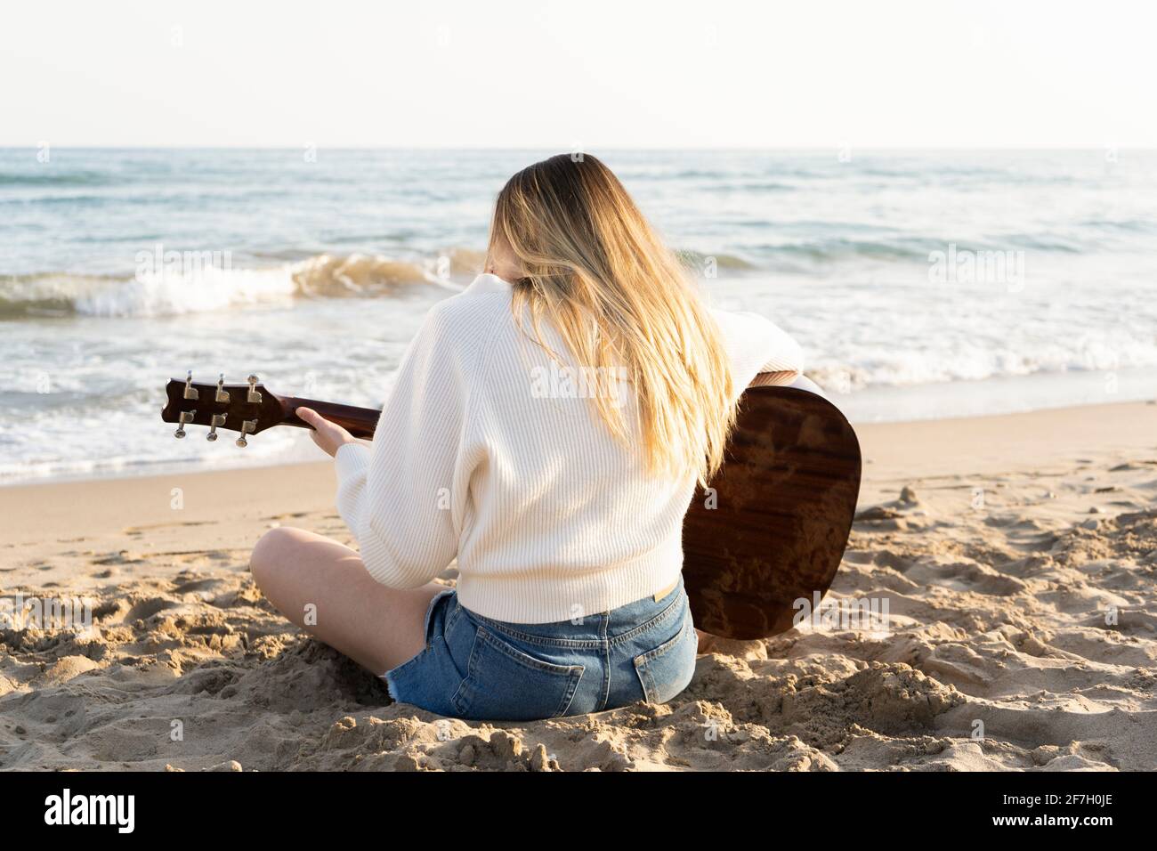 Jeune belle femme jouant de la guitare acoustique sur la plage au coucher  du soleil.Femme appréciant les vacances d'été en plein air sur la plage de  sable Photo Stock - Alamy