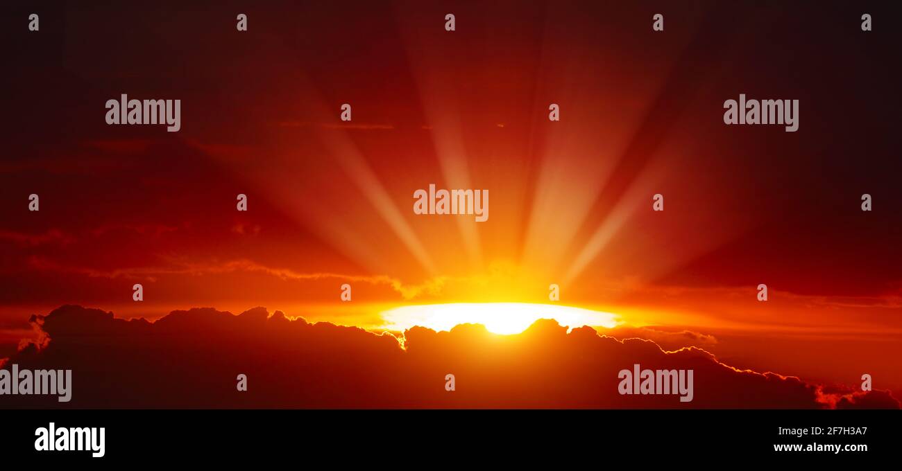 Coucher de soleil majestueux avec des rayons de soleil lumineux sur le ciel rouge. Banque D'Images