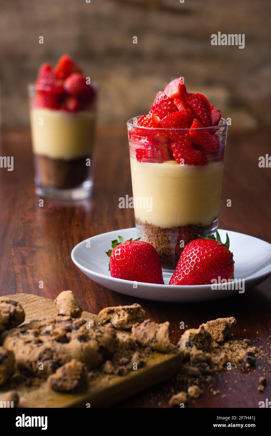 Un verre rempli de biscuits croquants et de pudding à la vanille et garni de fraises Banque D'Images