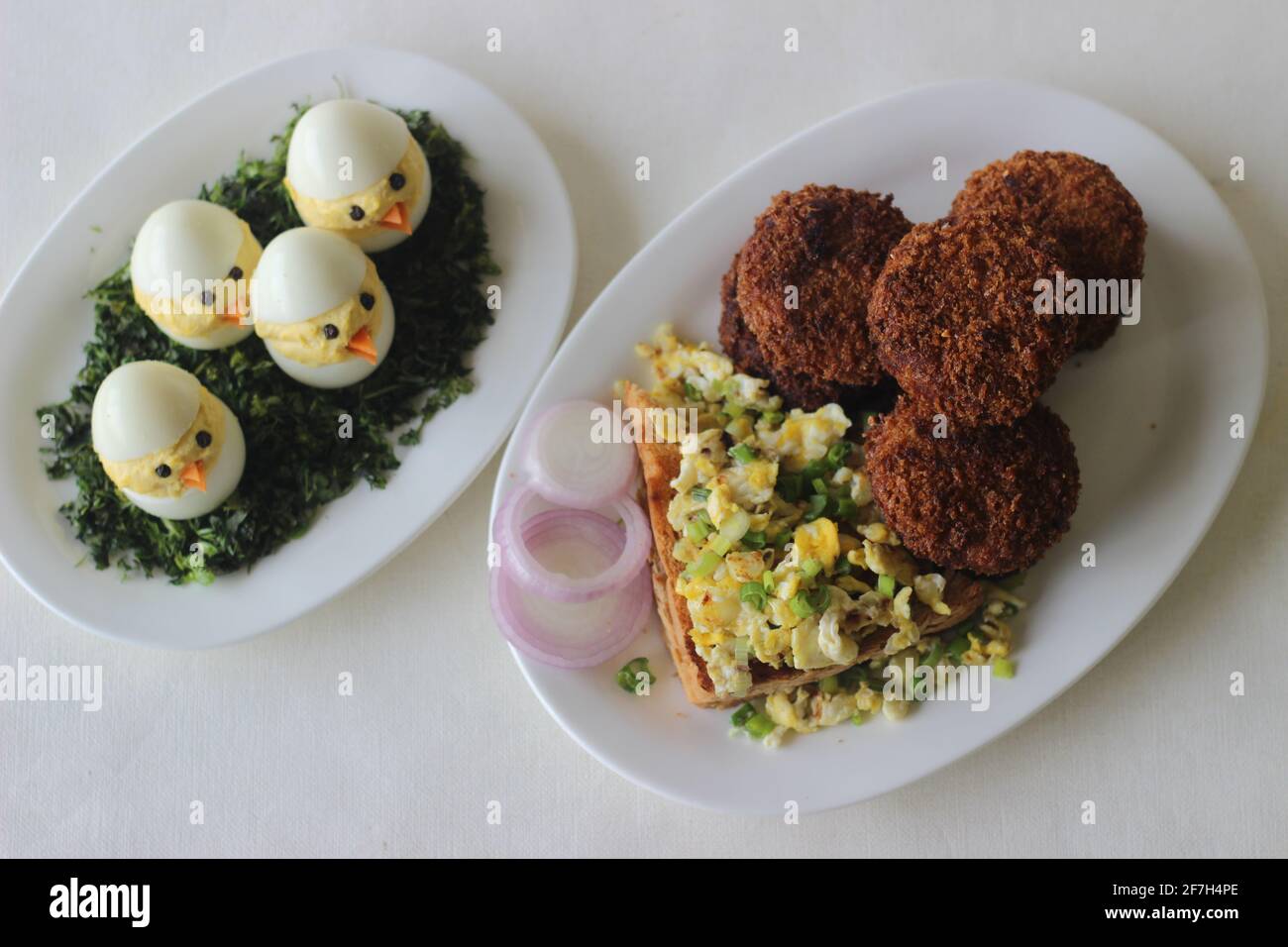 Petit-déjeuner de Pâques avec côtelettes de poulet, pain, œufs brouillés et œufs de Pâques. Prise de vue sur fond blanc. Banque D'Images