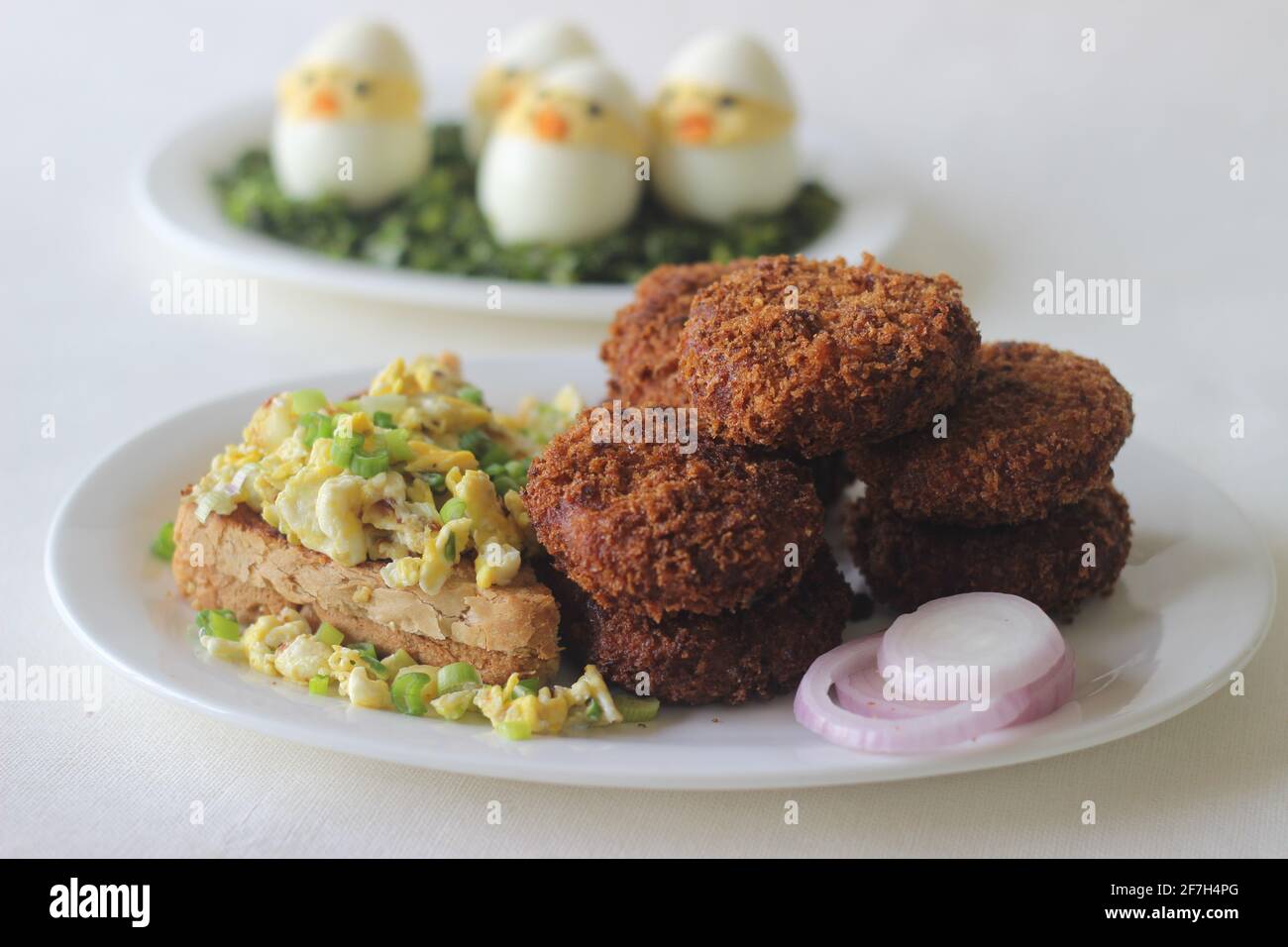 Petit-déjeuner de Pâques avec côtelettes de poulet, pain, œufs brouillés et œufs de Pâques. Prise de vue sur fond blanc. Banque D'Images
