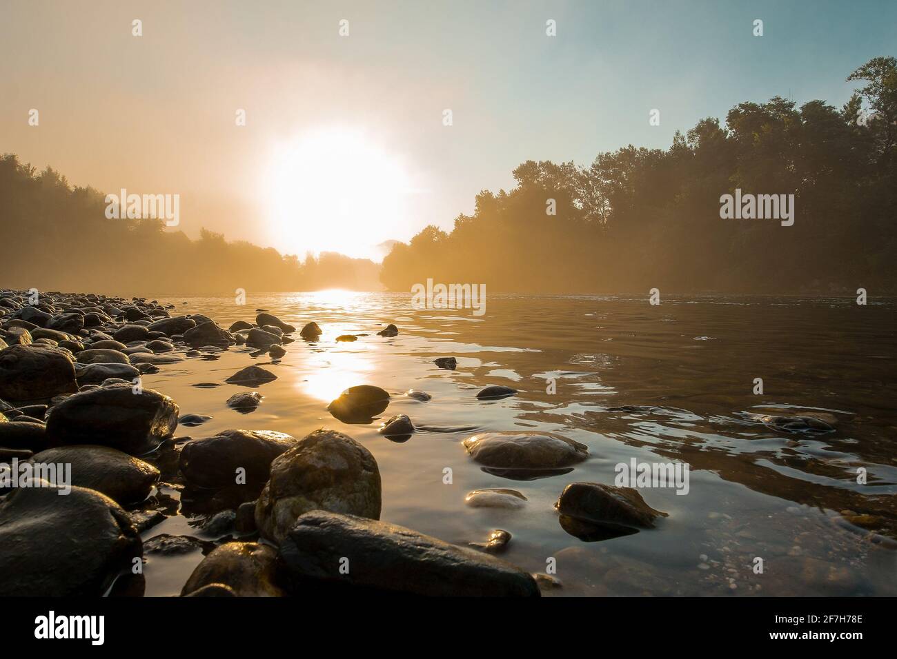 Panorama brumeux d'une rivière et d'une rive avec des pavés en début de matinée. Cadre mystique pendant une heure tôt le matin. Banque D'Images