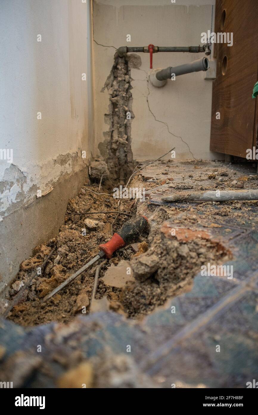 Tuyau d'eau cassé dans un appartement. Trou visible dans le sol avec des carreaux, du vieux béton et des débris. Chantier de construction tout en essayant de remédier à un le d'eau Banque D'Images