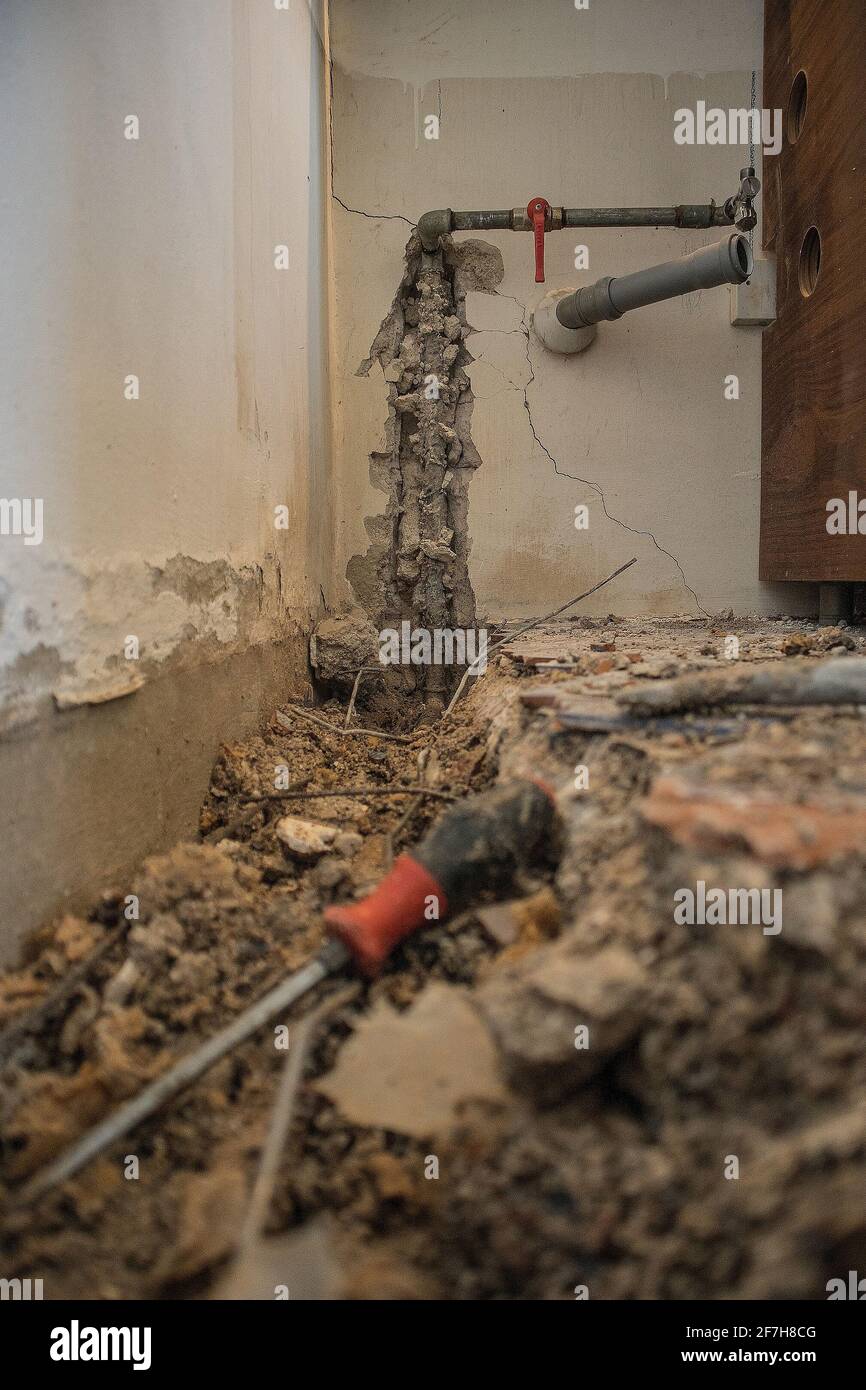 Tuyau d'eau cassé dans un appartement. Trou visible dans le sol avec des carreaux, du vieux béton et des débris. Chantier de construction tout en essayant de remédier à un le d'eau Banque D'Images