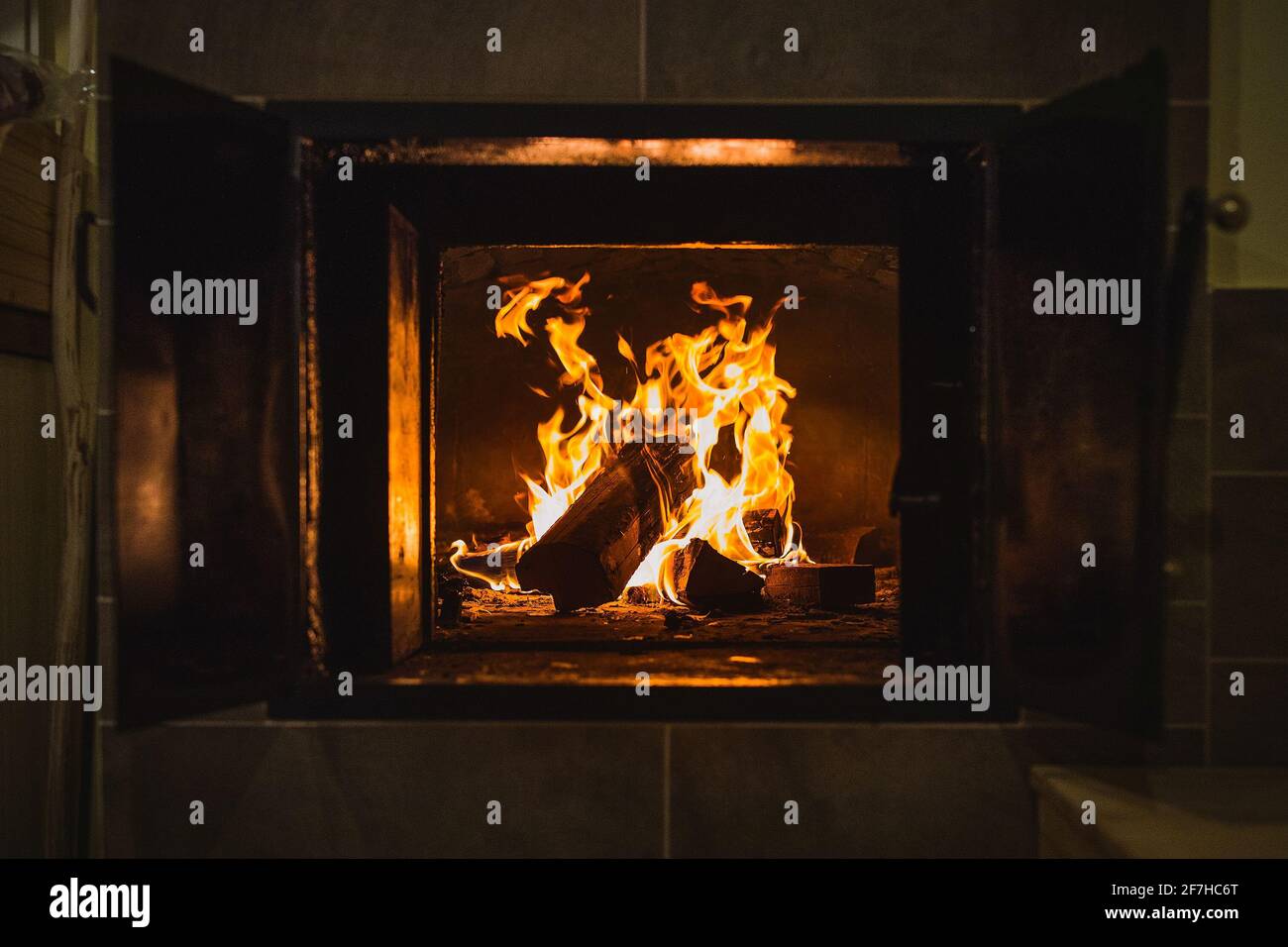 Gros plan d'une vieille cuisinière en briques ouvertes ou d'un four à pain dans une vieille maison. Feu ouvert avec des bûches dans un four à pain ou un four. Les portes d'un four sont ouvertes Banque D'Images Gros plan d'une vieille cuisinière en briques ouvertes ou d'un four à pain dans une vieille maison. Feu ouvert avec des bûches dans un four à pain ou un four. Les portes d'un four sont ouvertes Banque D'Images