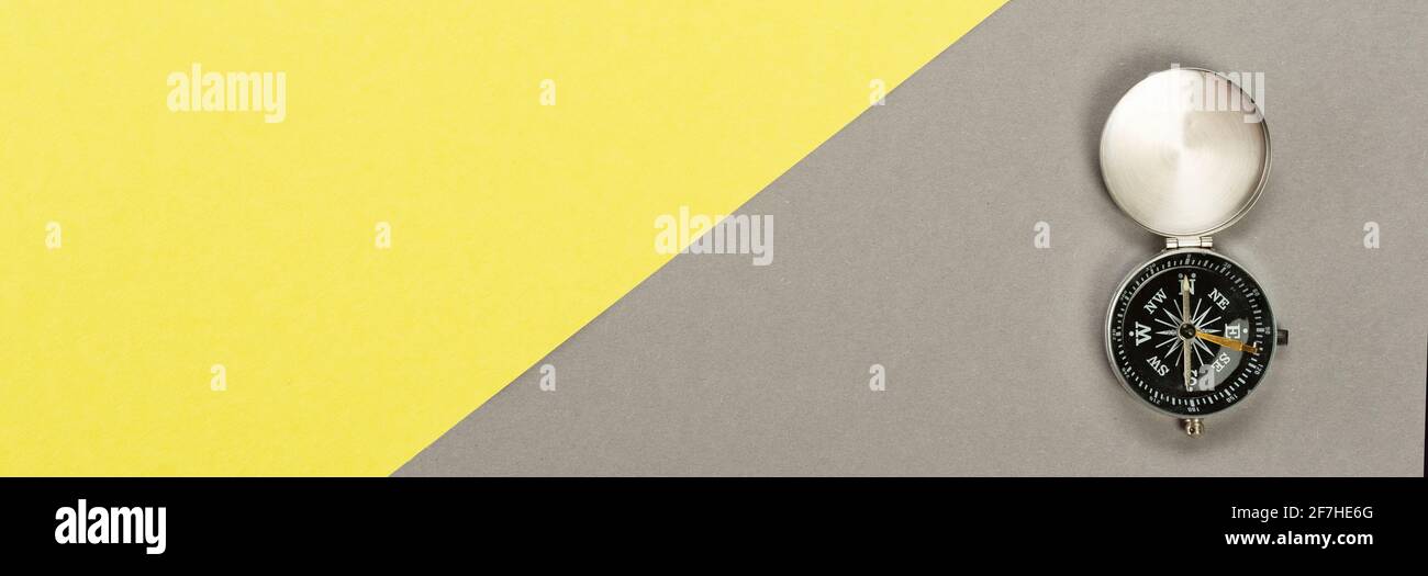 Compas sur fond gris jaune, concept de déplacement minimal. Banque D'Images