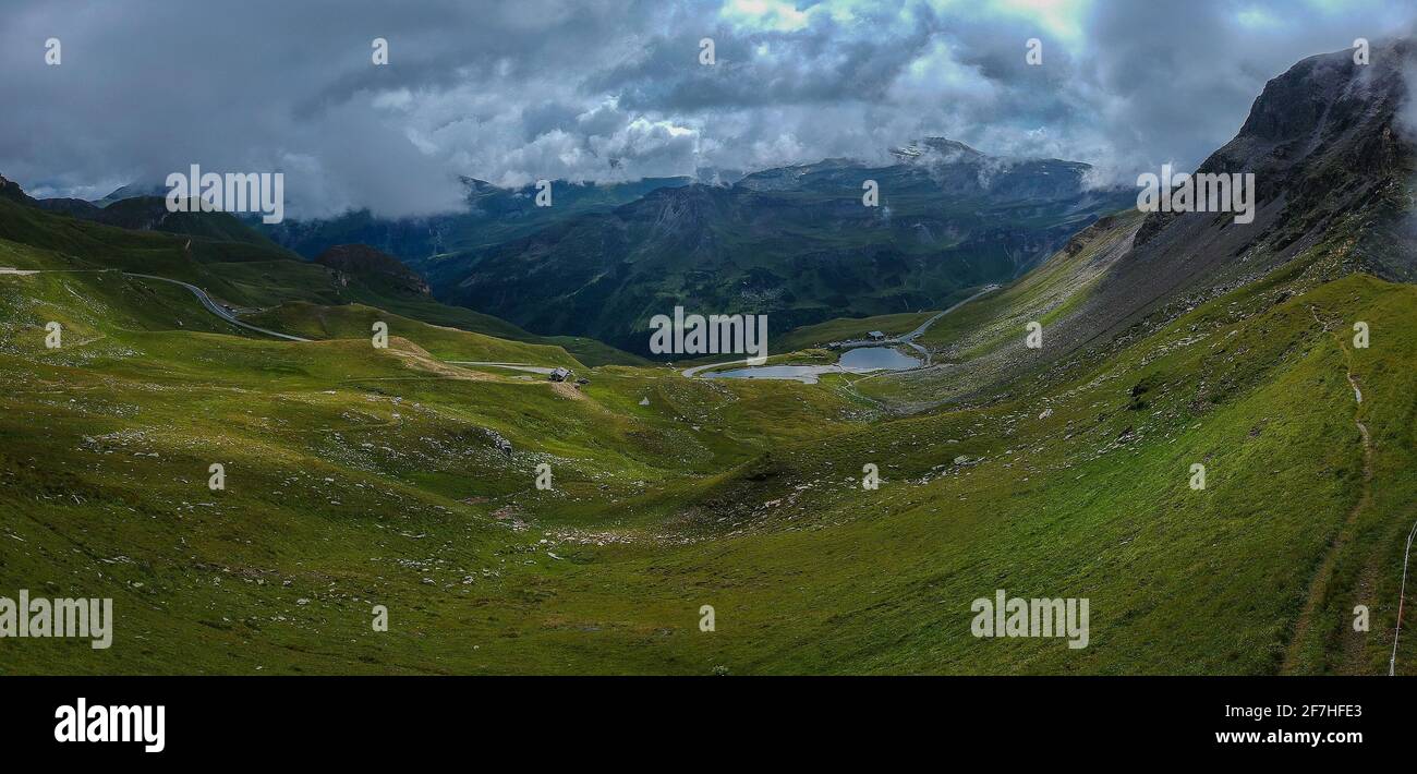 Panorama depuis Grossglockner passon une journée d'été avec de beaux nuages, des prairies verdoyantes et une route sinueuse vue ci-dessous. L'été sur le col de montagne. Banque D'Images