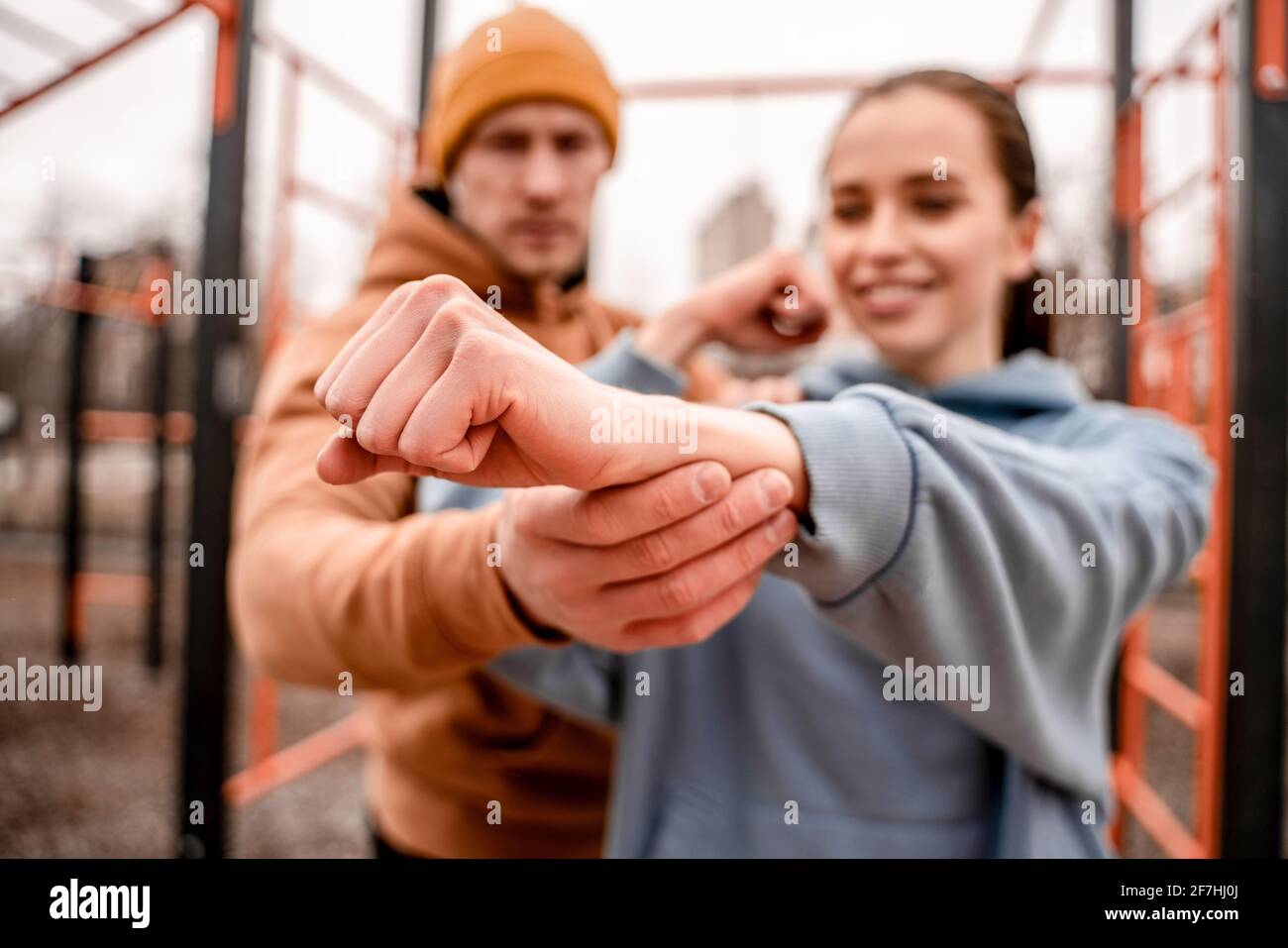 Gros plan jeune homme et femme s'étirant de muscle avant de courir sur le terrain de sport de rue. Maintien de la forme et concept sain. Banque D'Images