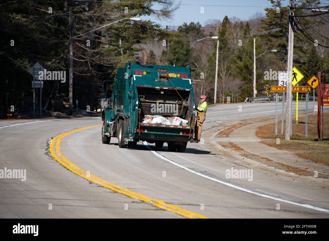 Un employé municipal de sexe masculin se trouvant à l'arrière d'un camion à ordures collectant des déchets dans le spéculateur, NY USA Banque D'Images