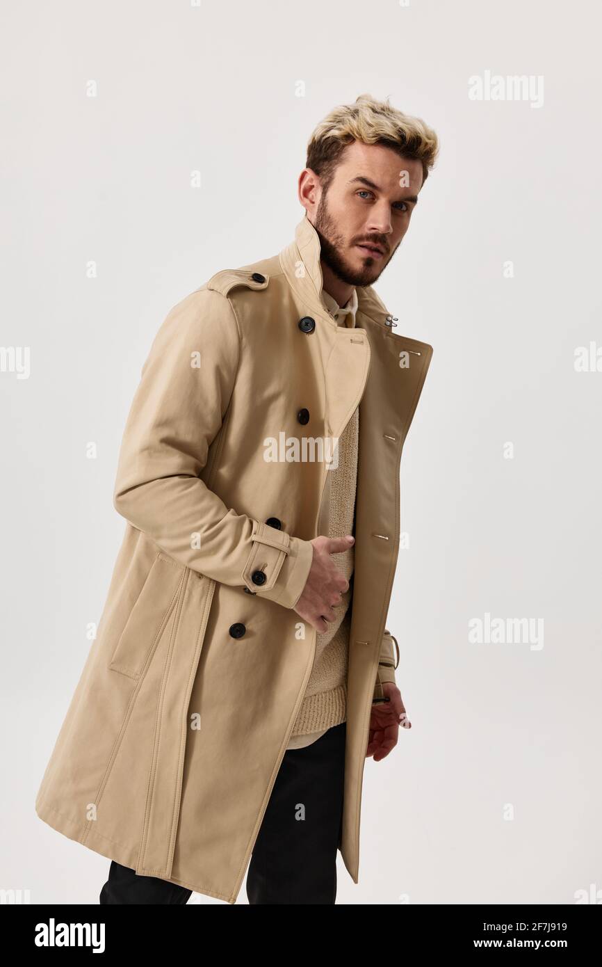 un homme dans un manteau beige plié sur le pantalon sur le côté et tendance  en costume de coiffure Photo Stock - Alamy