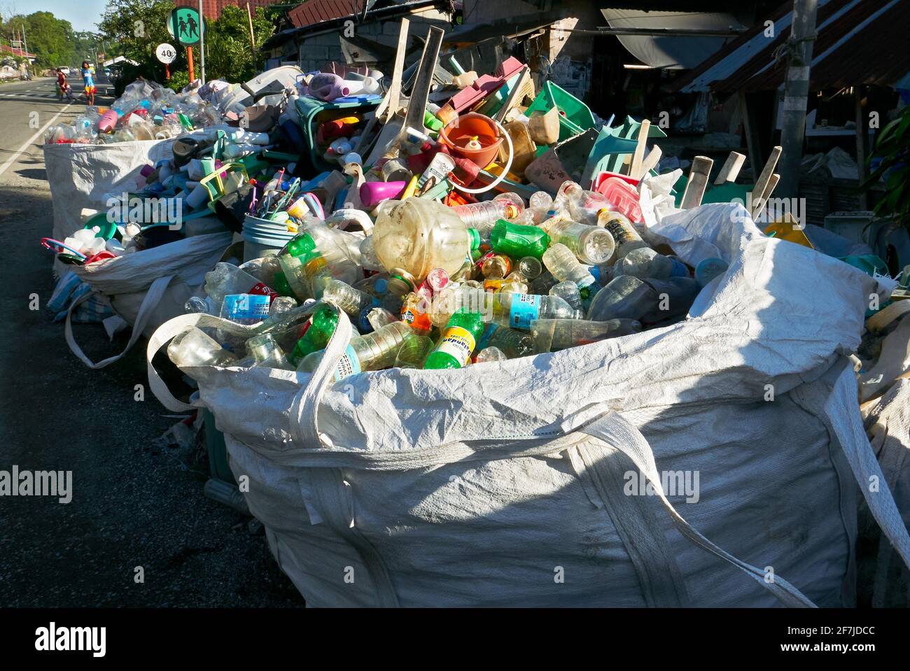 Boutique de malbouffe le long de la route avec des sacs pleins de collecte de bouteilles en plastique vides colorées pour le recyclage, province d'Aklan, Philippines, Asie Banque D'Images