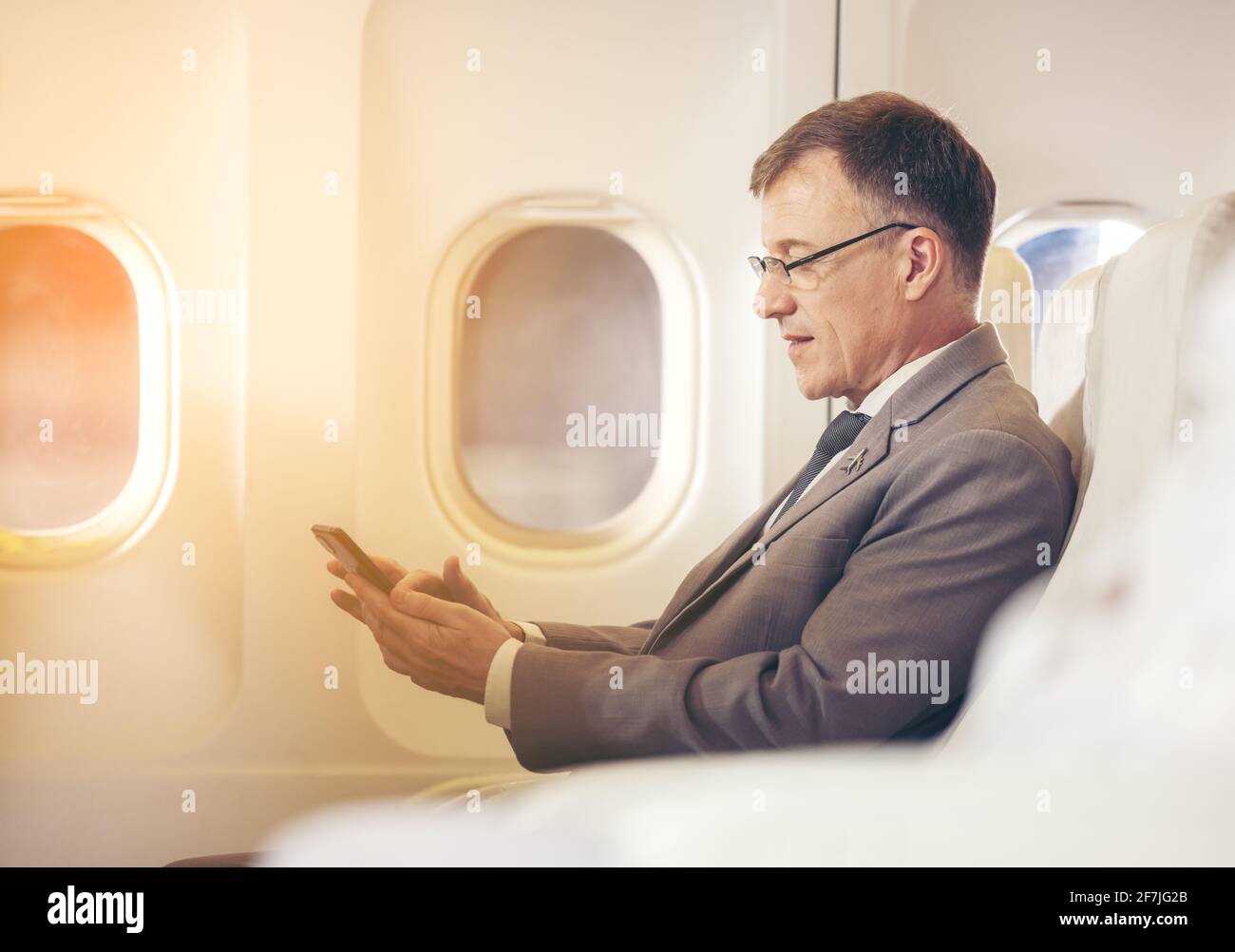 homme d'affaires avec costume assis à l'aide d'un smartphone dans le avion Banque D'Images