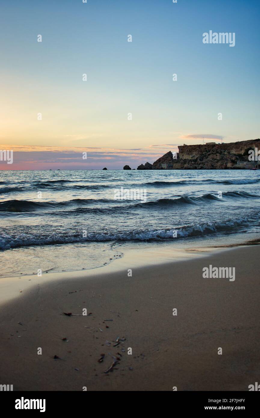 Bleu de l'eau de l'océan et un ciel coloré à Golden Bay, Malte, lors d'une chaude soirée d'automne. Banque D'Images