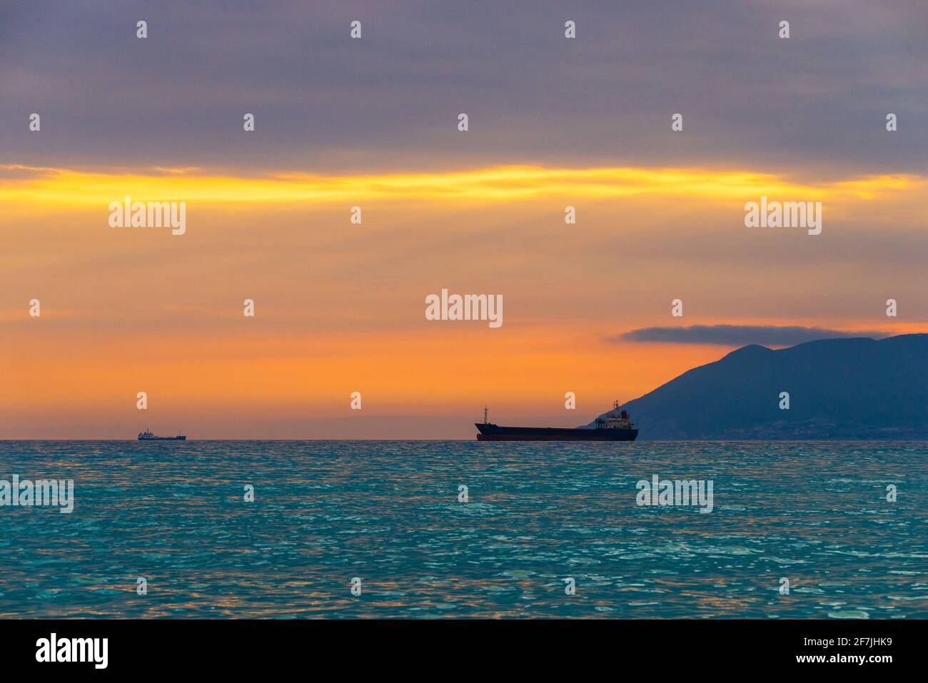 Un cargo navigue au coucher du soleil coloré. Banque D'Images