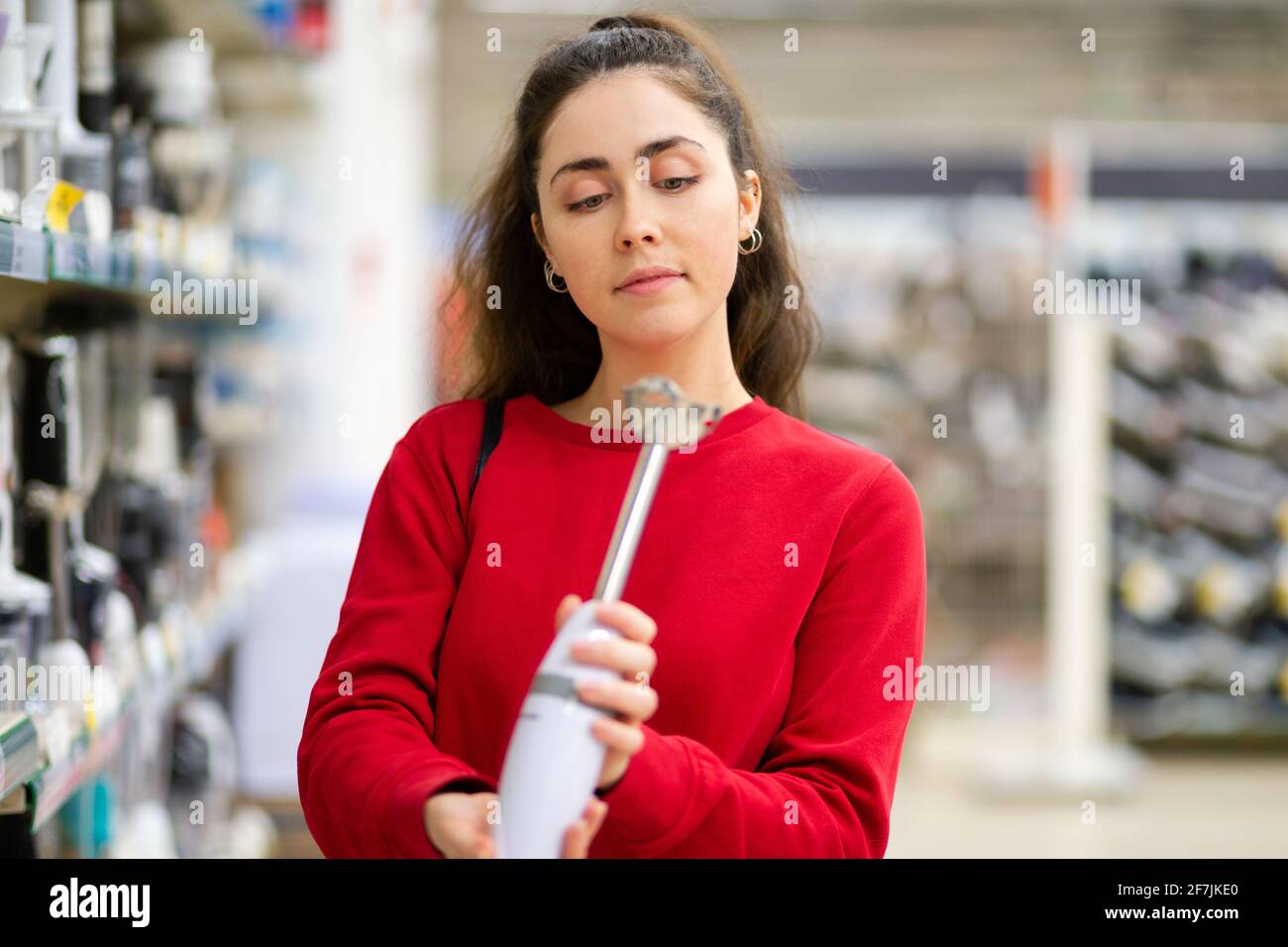 Une jeune femme choisit un blender dans un magasin d'électroménager. Vue  latérale. Le concept de consumérisme et de shopping Photo Stock - Alamy