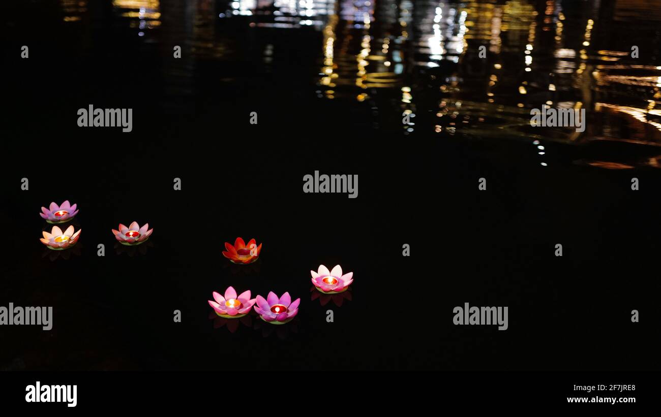 Lotus qui coule sur la rivière avec une bougie éclairée, petite ville éclairée avec un reflet sur l'eau. Banque D'Images