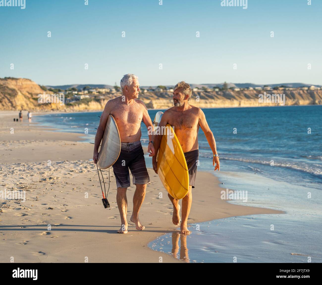 Deux hommes matures marchant avec des planches de surf sur la belle plage appréciant le paradis et le mode de vie de retraite. Une tenue attrayante pour les adultes Banque D'Images