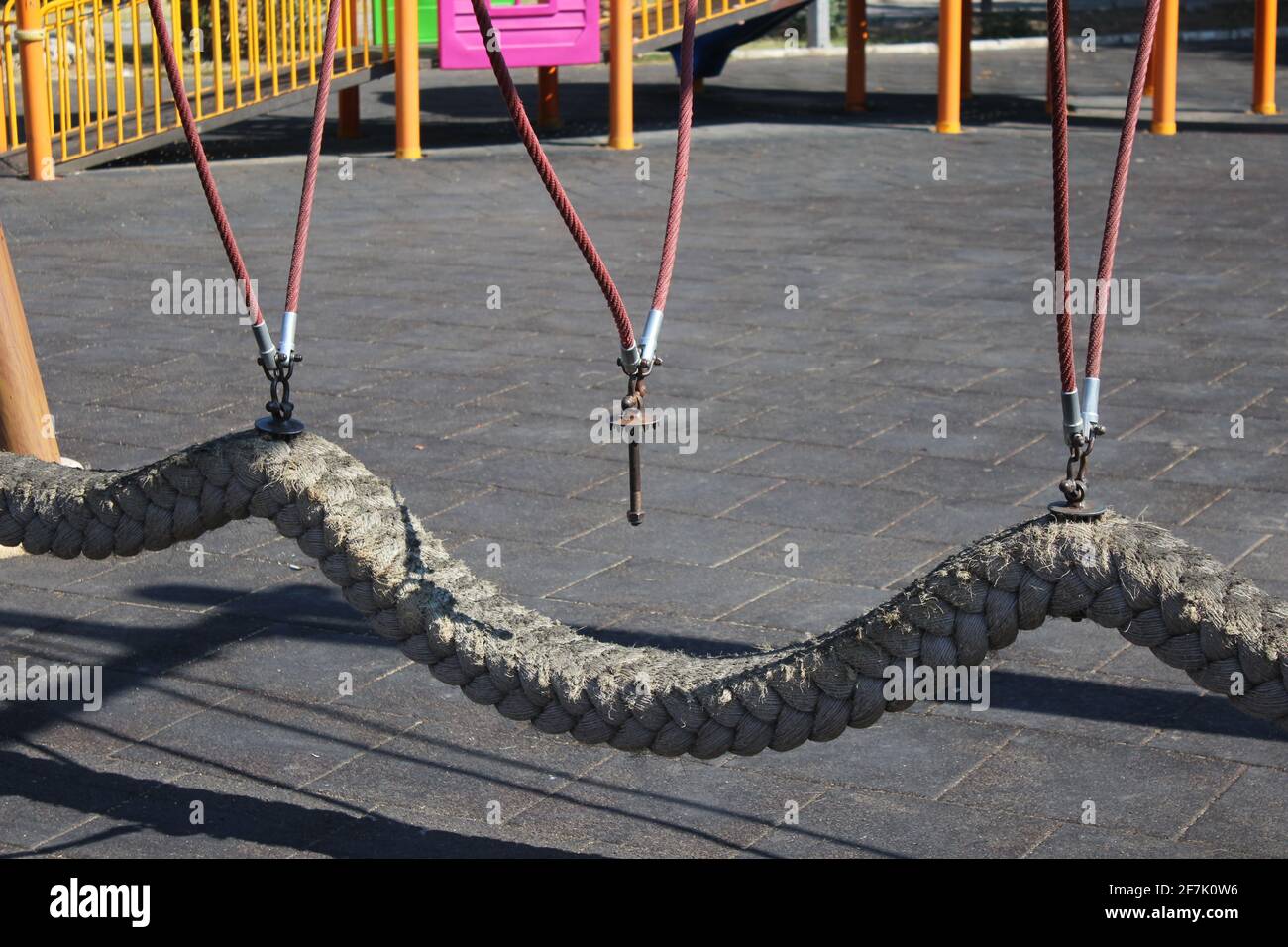 Une forte corde balançoire avec suspension cassée dans un terrain de jeu à midi. Banque D'Images