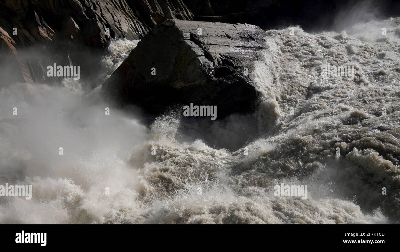 Une énorme pierre au milieu de la rivière avec écoulement rapide de l'eau dans la gorge de tigre bondissant de Lijiang. Banque D'Images