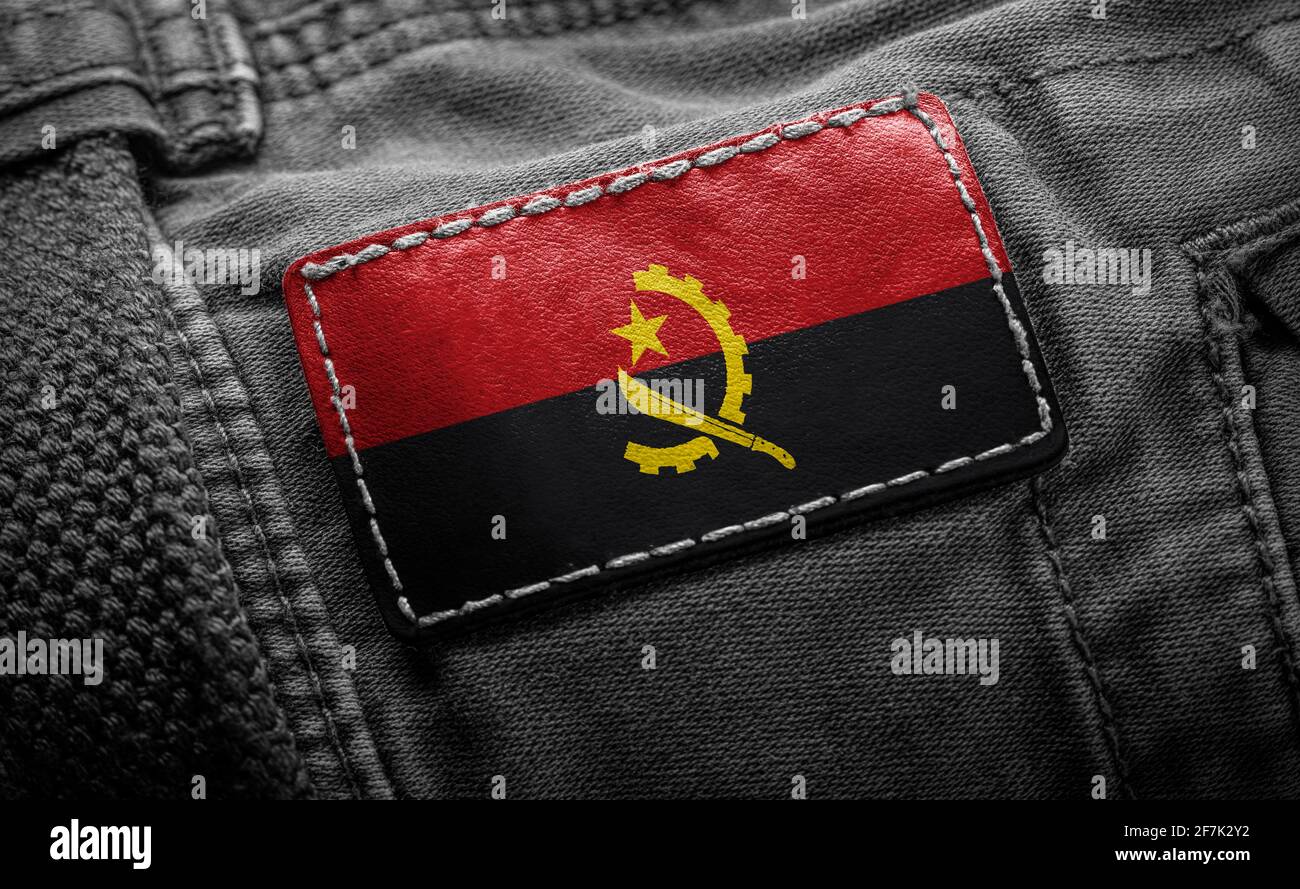 Étiquette sur les vêtements foncés sous la forme du drapeau De l'Angola Banque D'Images