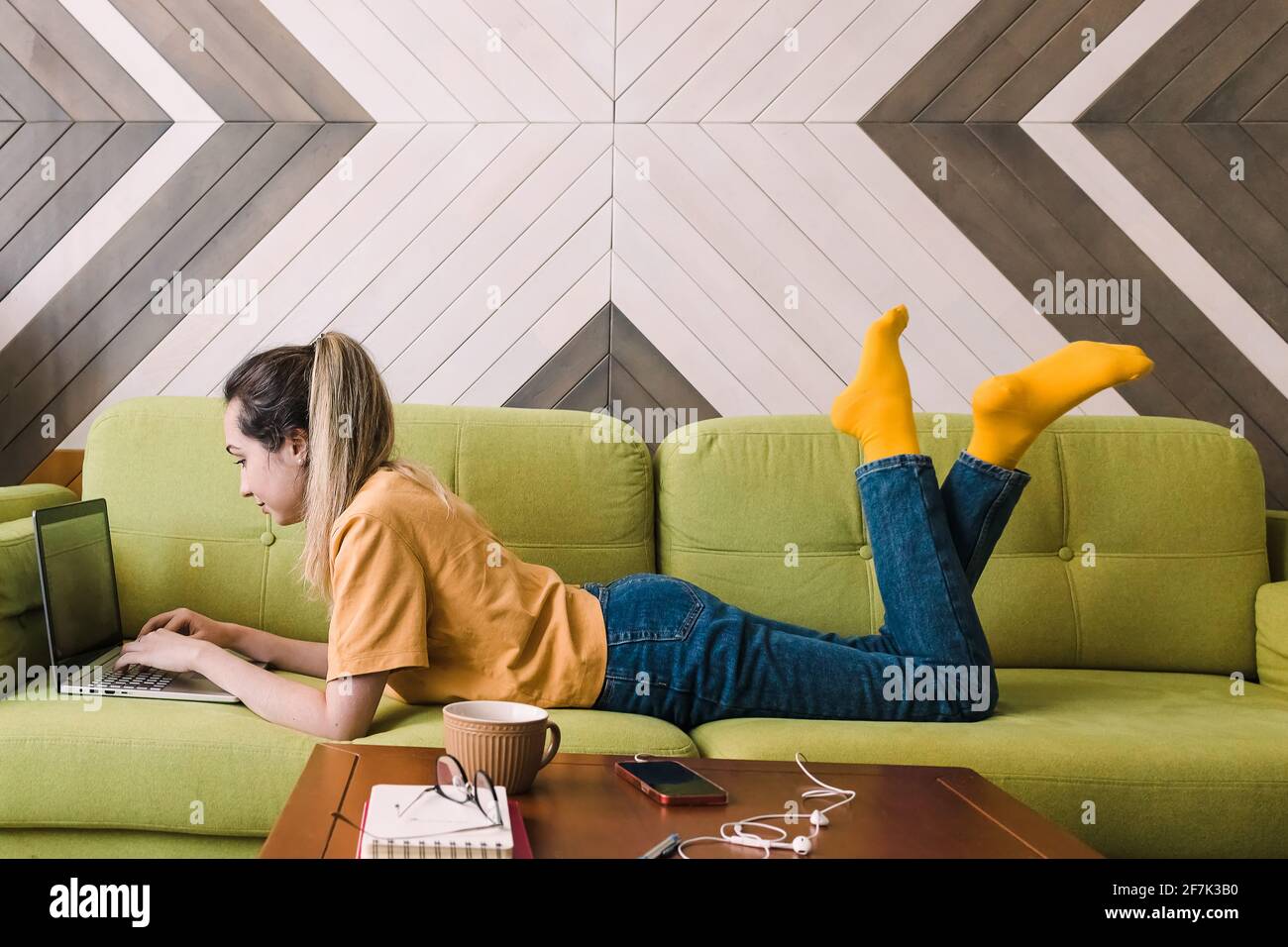 Jeune femme allongé sur le canapé avec son ordinateur portable Banque D'Images