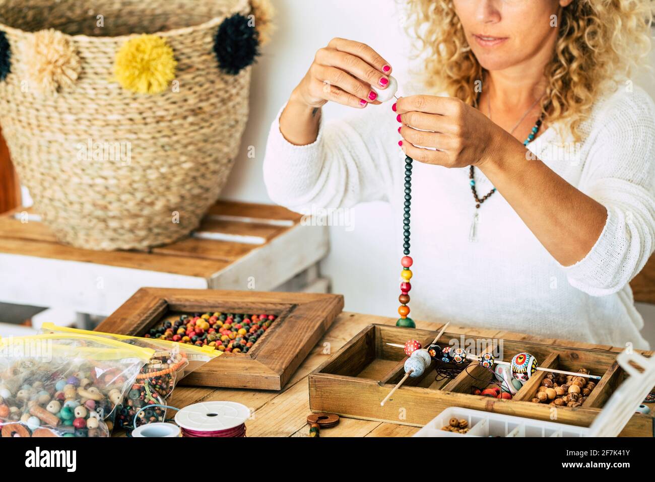 Femme à la maison faire des bijoux faits main. Boîte avec perles sur une  ancienne table en bois. Voir avec les mains de femme - tutoriel pour  apprendre à faire des bracelets