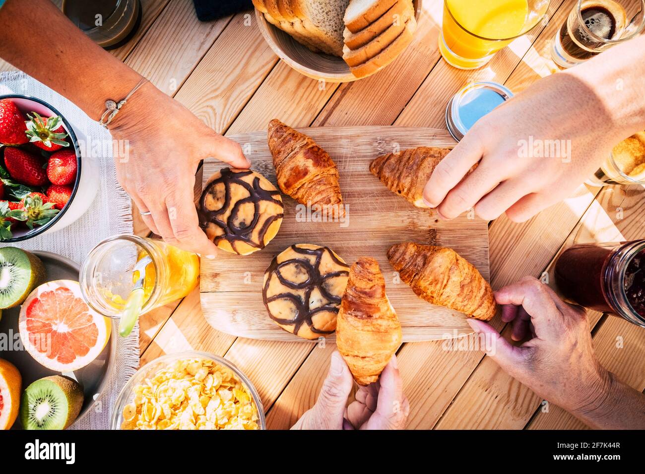 Vue de dessus de la table avec la nourriture du petit déjeuner et les personnes qui mangent ensemble dans l'amitié - heure du matin en famille et boulangerie fraîche croissant - vue rapprochée des mains pi Banque D'Images