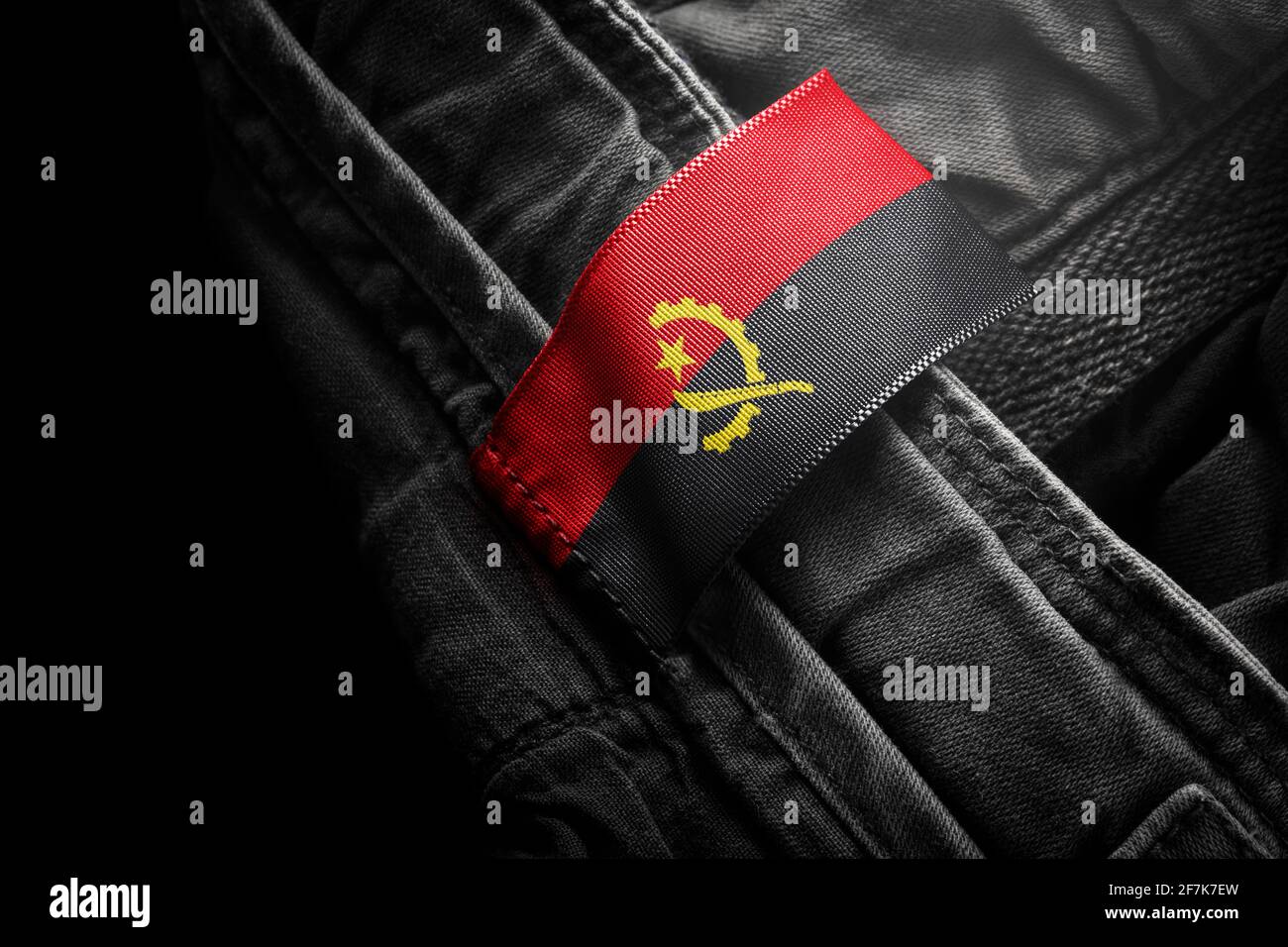 Étiquette sur les vêtements foncés sous la forme du drapeau De l'Angola Banque D'Images