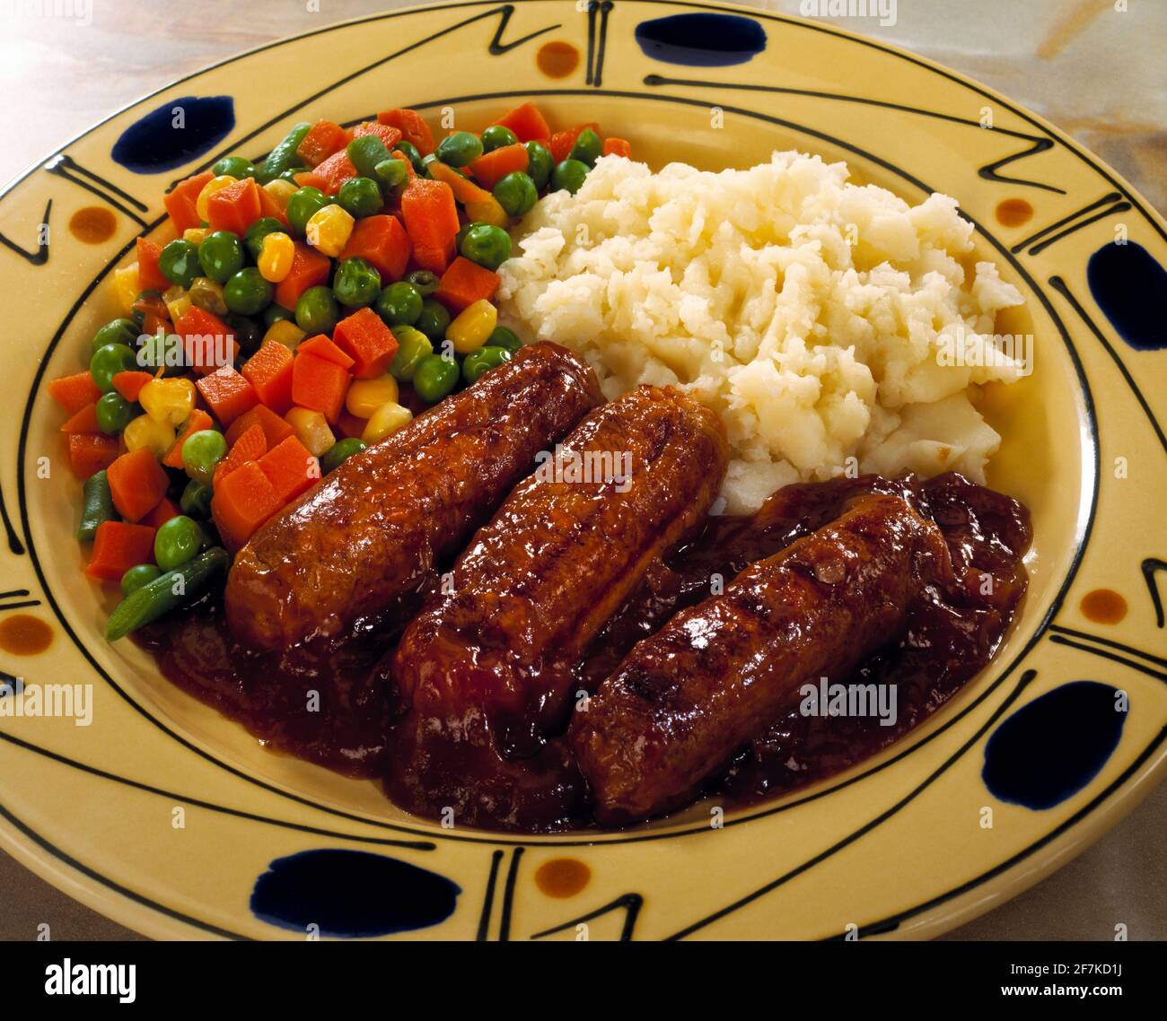 Saucisse, purée de pommes de terre, légumes mélangés et sauce sur une assiette Banque D'Images