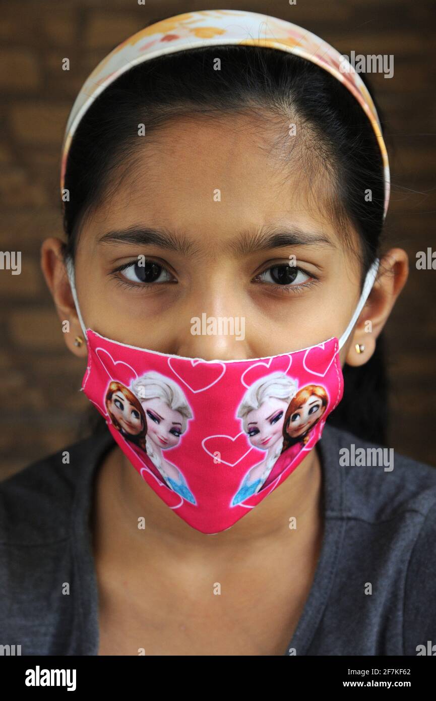 Petite fille indienne ou asiatique portant un masque facial comme protection personnelle contre la pollution de l'air ou le coronavirus COVID-19. Banque D'Images