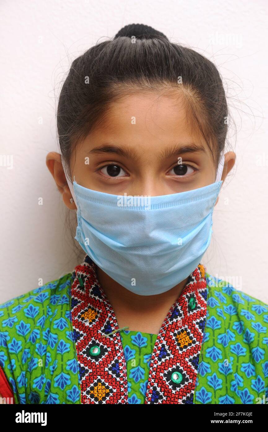 Petite fille indienne ou asiatique portant un masque facial comme protection personnelle contre la pollution de l'air ou le coronavirus COVID-19. Vêtements taille basse pour jeunes dans un masque de protection Banque D'Images