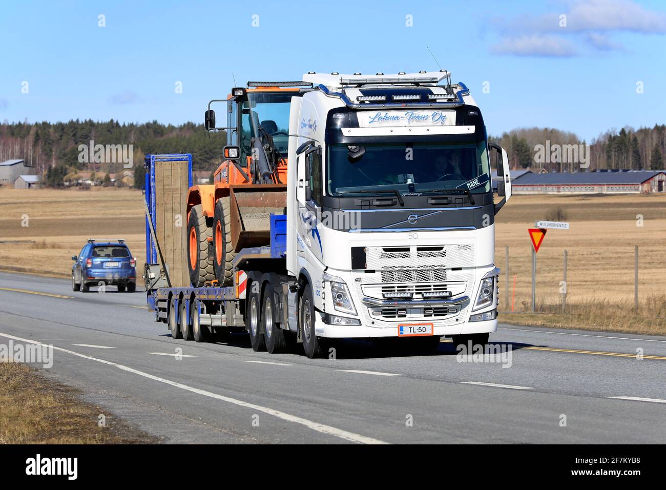 Le camion Volvo FH 540 de Lahma-Trans Oy transporte une chargeuse sur pneus Doosan sur une remorque surchargée le long de l'autoroute au printemps. Jokioinen, Finlande. 1er avril 2021. Banque D'Images