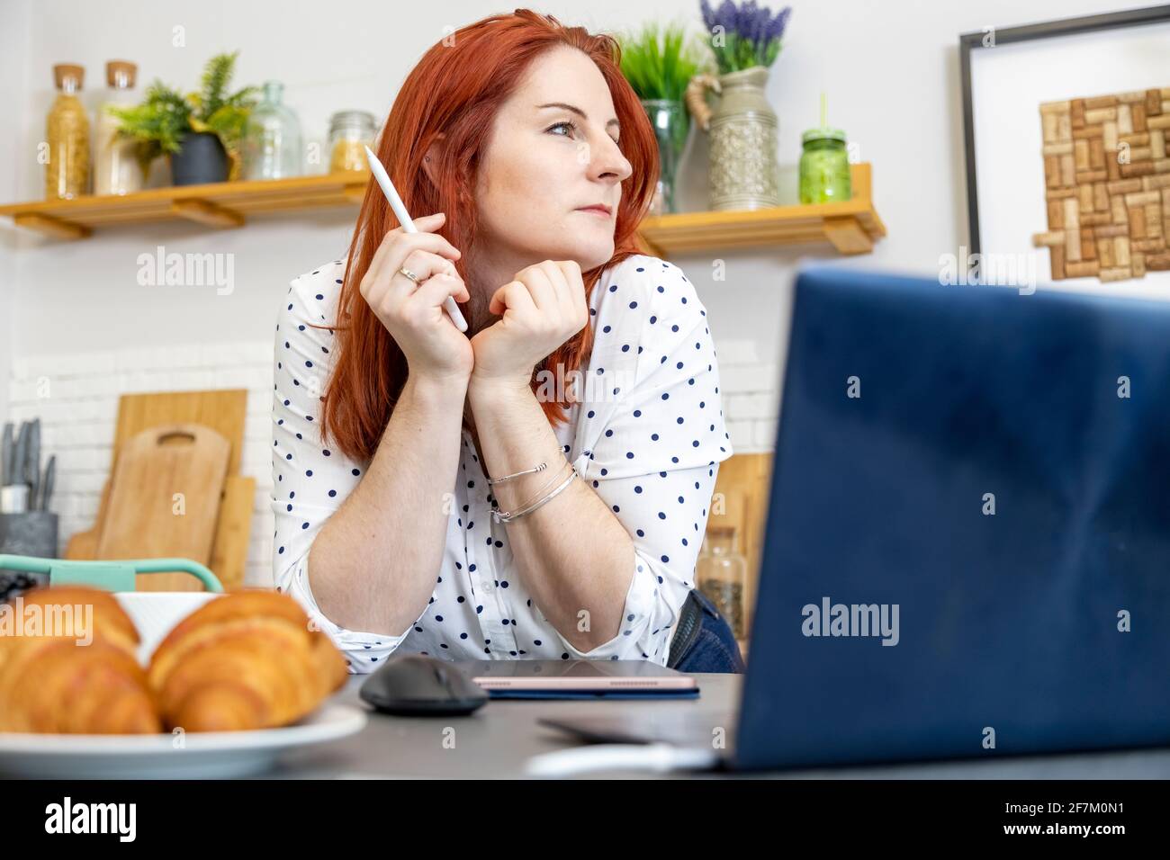 une femme attirante se trouve devant un ordinateur dans la cuisine. blogger écrit un message sur internet. auteur de contenu, spécialiste du droit d'auteur. création ima Banque D'Images