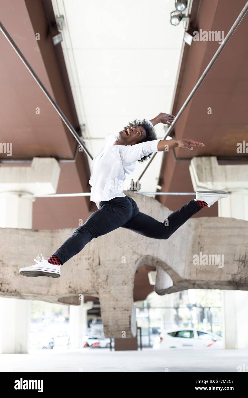 Danseuse afro-américaine effectuant un saut acrobatique dans la ville en plein air. Concept de danse urbaine. Espace pour le texte. Banque D'Images