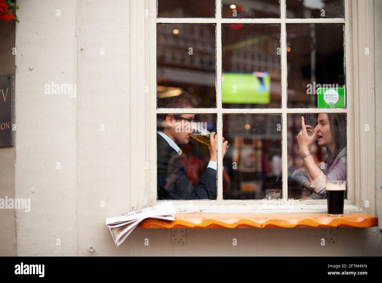 30s jeunes professionnels, homme et femme de la région parlant dans le pub, boire de la bière par la fenêtre. Vie quotidienne à Londres, Royaume-Uni. Août 2015 Banque D'Images