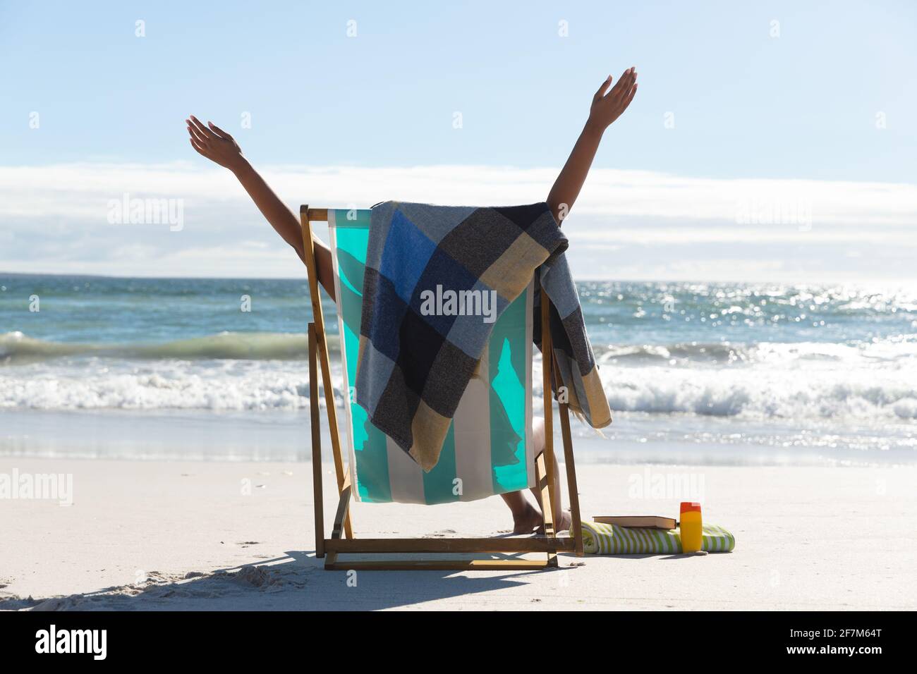 Femme de course mixte sur la plage de vacances assis dans le transat étirant Banque D'Images