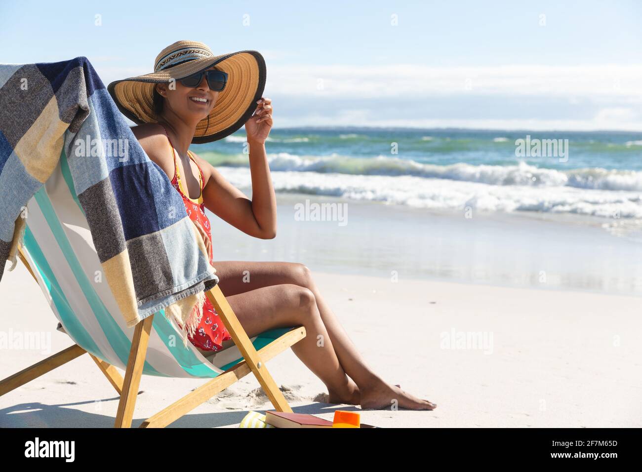 Portrait d'une femme de race mixte souriante sur la plage de vacances assis chaise longue Banque D'Images