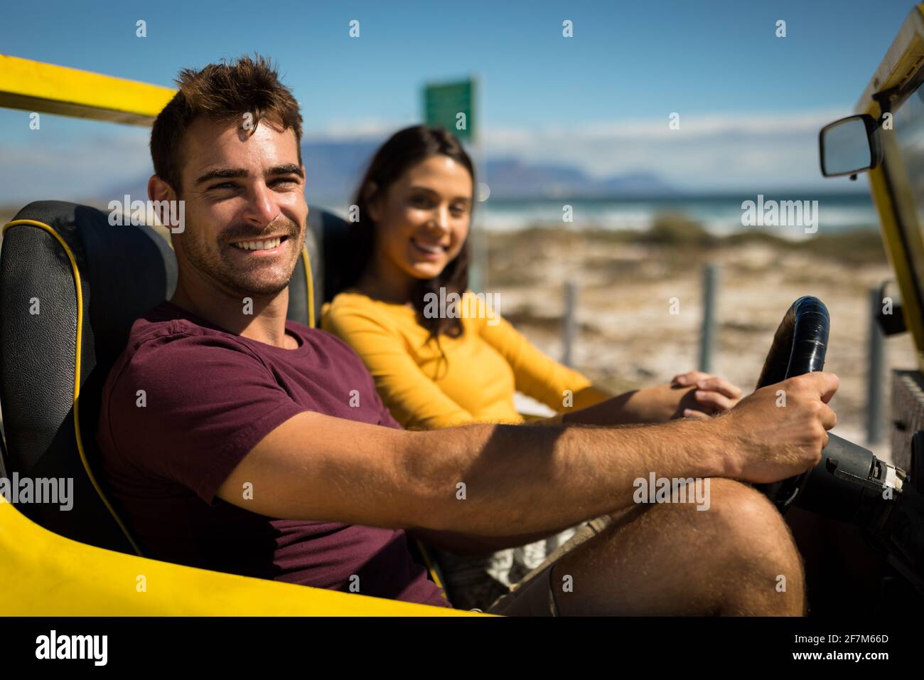 Portraits d'un couple caucasien heureux qui cherche un appareil photo assis promenade sur la plage en bord de mer Banque D'Images