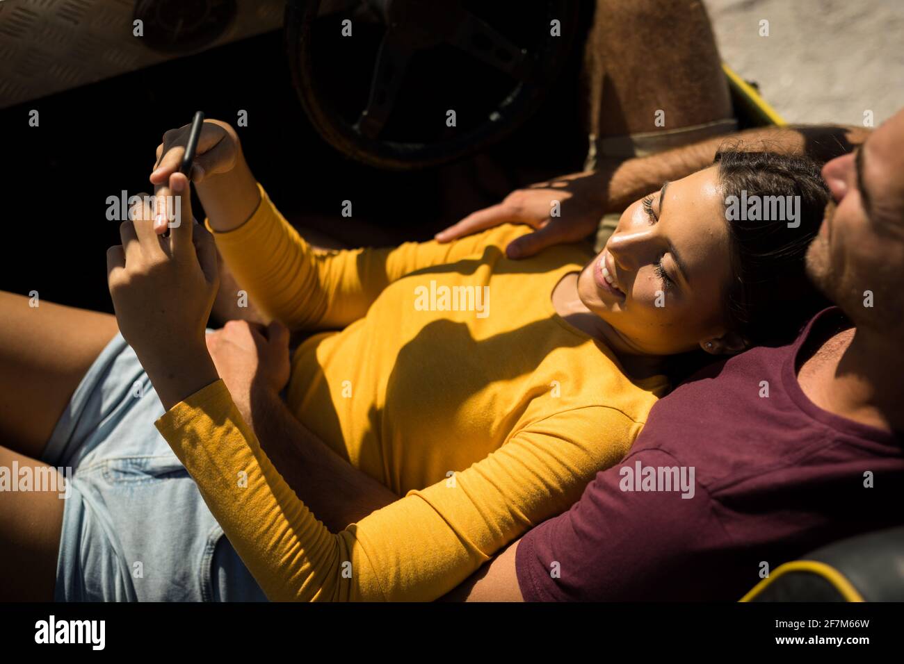 Couple caucasien couché sur une promenade de plage au bord de la mer à l'aide d'un smartphone Banque D'Images