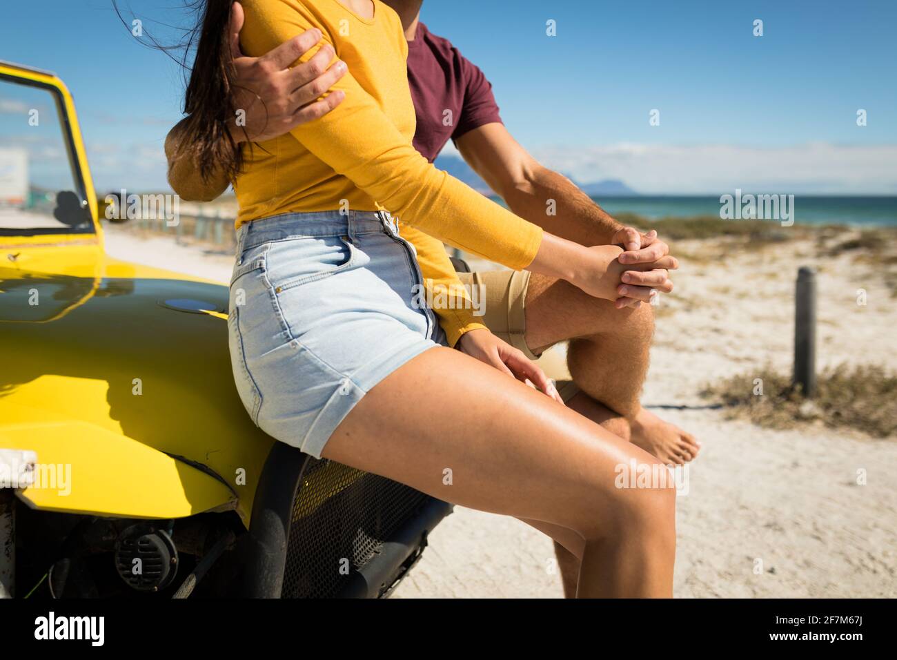 Milieu de section de couple caucasien heureux assis sur la plage buggy à côté la mer tient les mains Banque D'Images