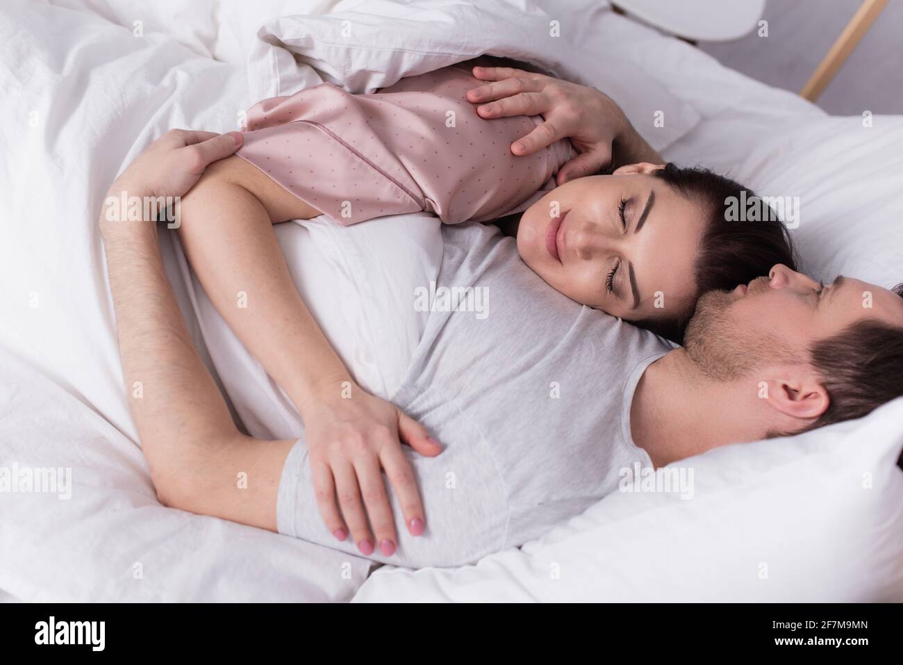 Homme adulte qui embrasse sa femme en étant allongé sur le lit Photo Stock  - Alamy