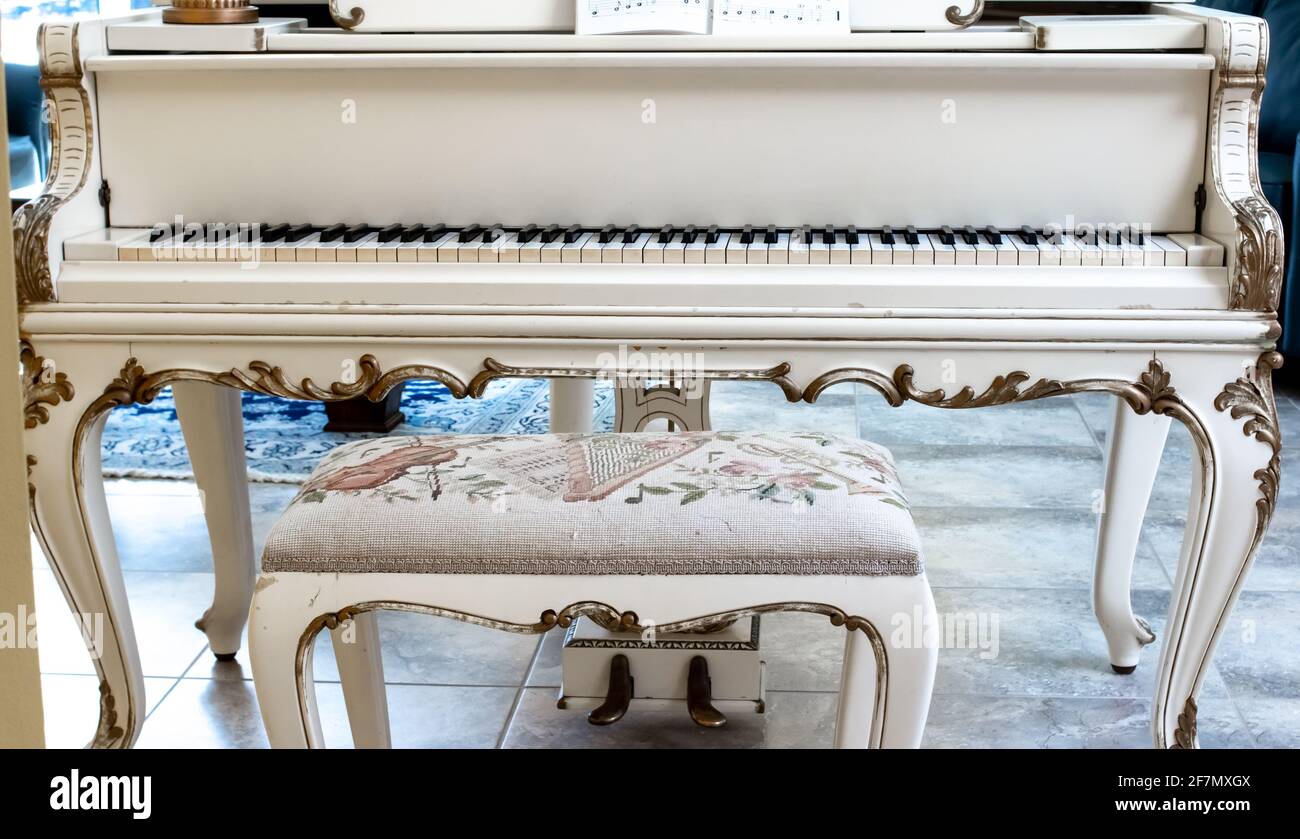 Un magnifique piano à queue blanc avec des touches d'ivoire et un banc  rembourré orné sur un carrelage beige. Intérieur, Londres, Canada. Prise de  vue directe Photo Stock - Alamy