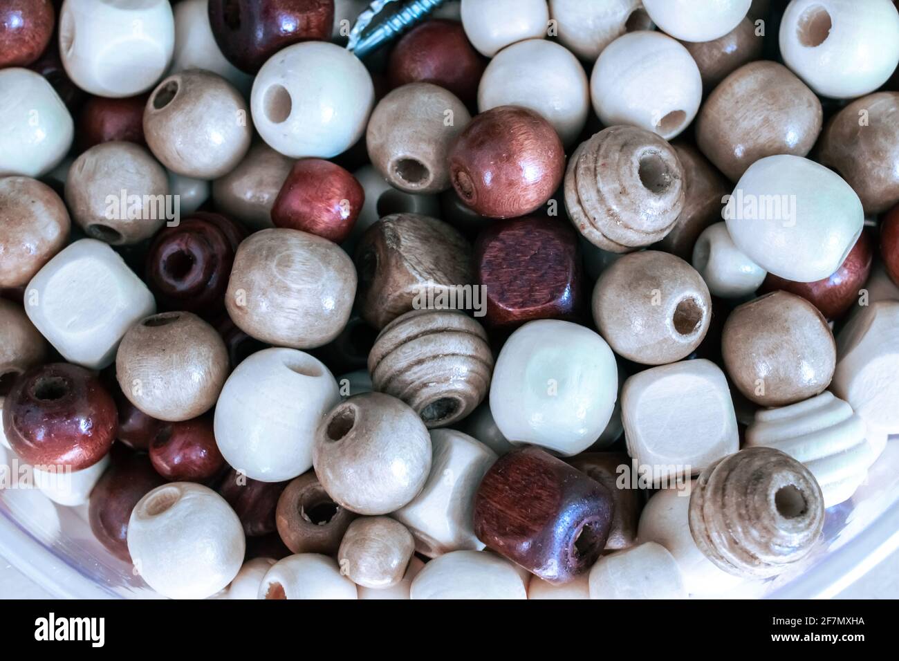 Un bol de perles en bois assorties, marron, rouge, orange et blanc, avec une vis argentée au milieu. Tourné le 2021 février en Ontario, Canada. Banque D'Images