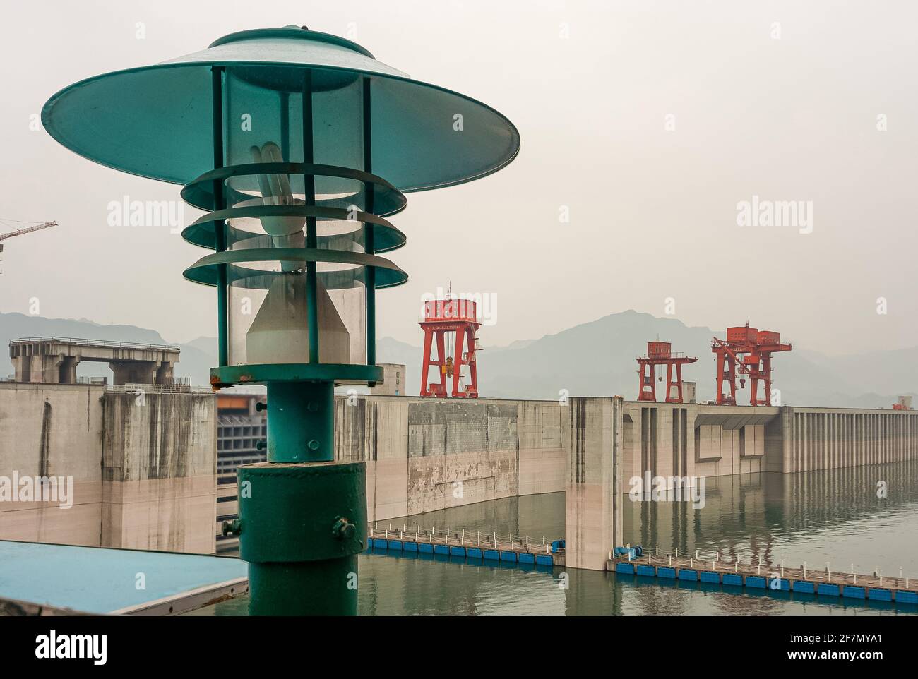 Barrage des trois Gorges, Chine - 6 mai 2010 : fleuve Yangtze. Lanterne verte à l'avant avec barrage à l'arrière sous le ciel fané. Verrou de commande de projecteur rouge, levage de porte Banque D'Images