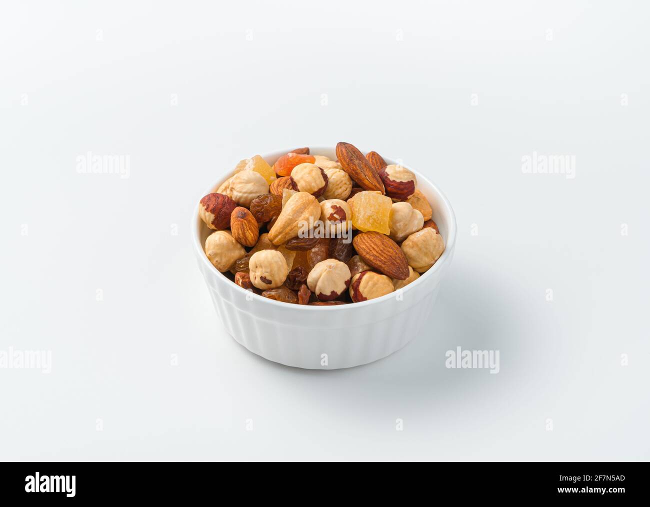 Un mélange de noix et de fruits secs dans un bol blanc sur fond clair. Vue latérale, gros plan. Banque D'Images