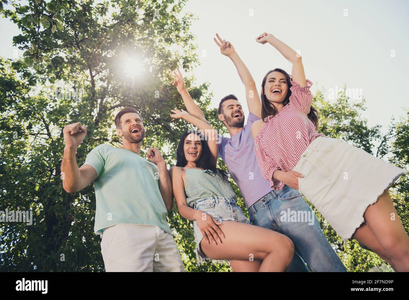 Photo de vue à angle bas positive jeunes hommes et femmes ami gagnez des mains levées poings yell ouais temps libre en plein air stationnement Banque D'Images