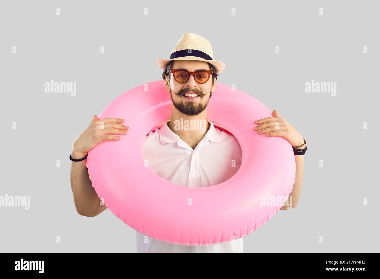 Portrait d'un homme avec un cercle gonflable rose autour de son cou qui est prêt pour les vacances d'été. Banque D'Images