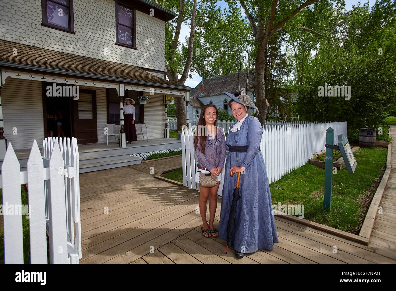 Pleine corps heureux philippin voyageur et femme dans la vieille mode costume souriant et regardant la caméra tout en se tenant près de la clôture À fort Edmonton, en Alberta Banque D'Images