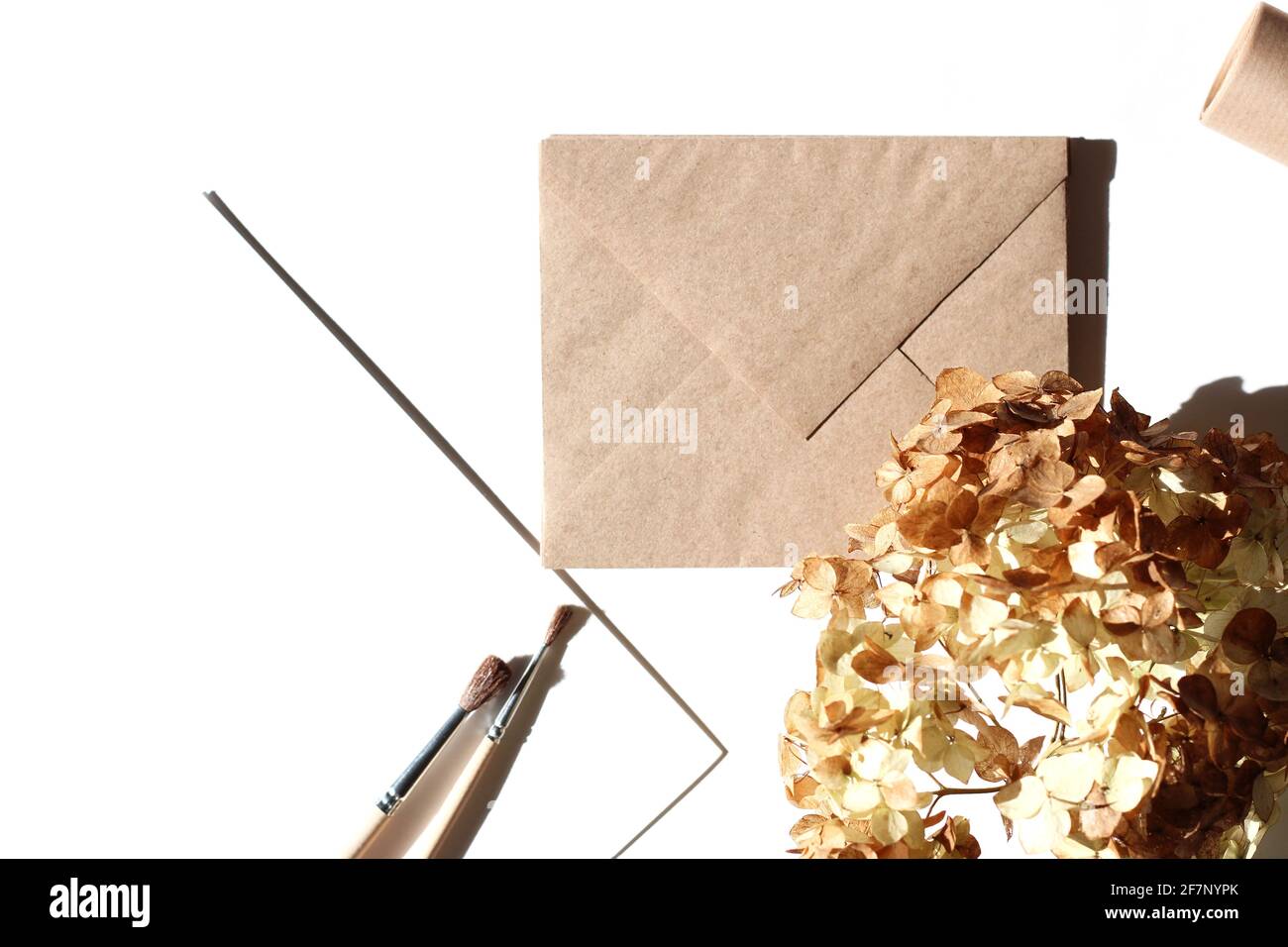 Mise à plat minimale de l'artiste. Enveloppes, pinceaux et papier Kraft sur fond blanc. Concept de conception créative. Banque D'Images